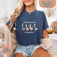 Person wearing a navy blue t-shirt with a graphic and text, sitting on a couch.
