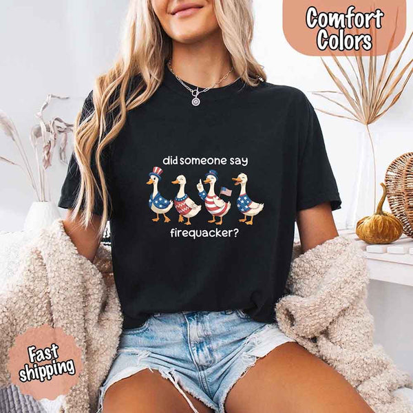 Person wearing a black t-shirt with a graphic of ducks and text, sitting indoors.