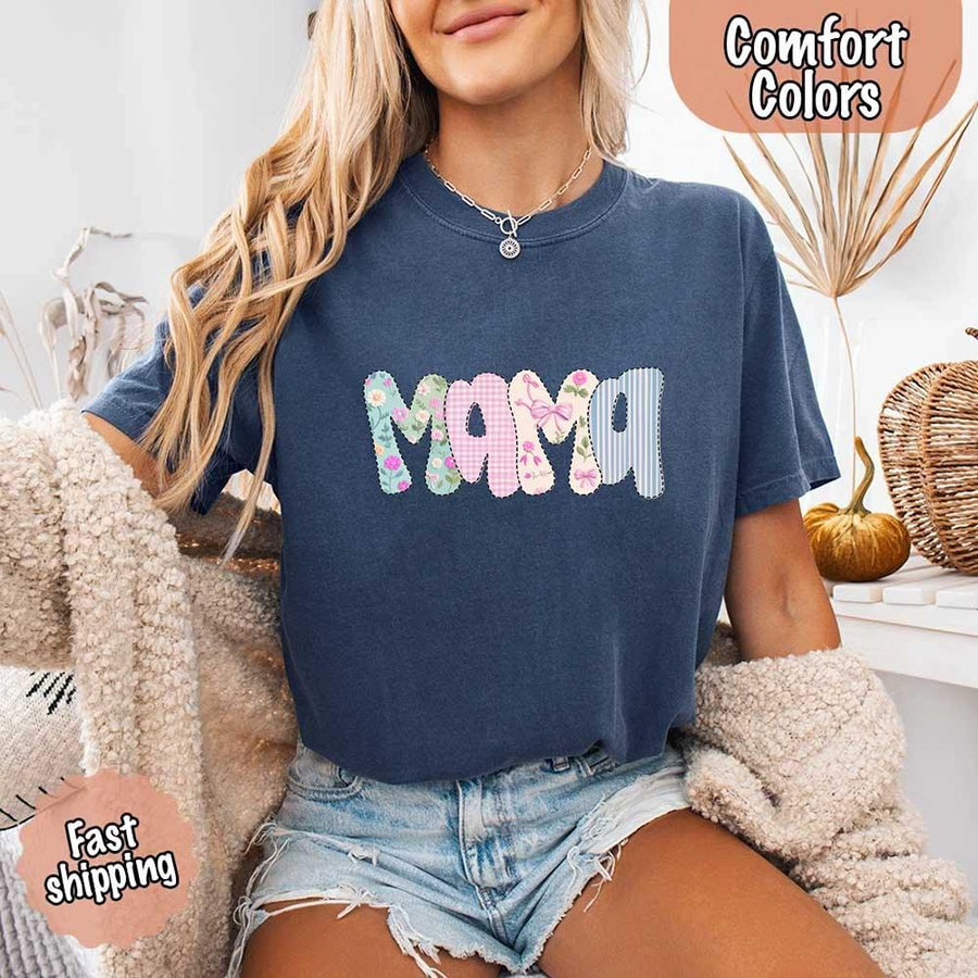 Woman wearing a navy blue t-shirt with 'MAMA' in colorful letters, sitting on a couch.