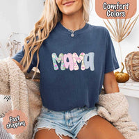 Woman wearing a navy blue t-shirt with 'MAMA' in colorful letters, sitting on a couch.