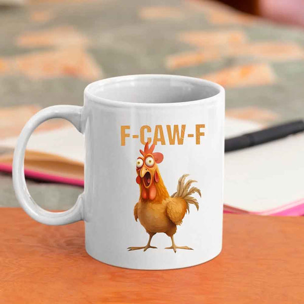 White mug with a cartoon chicken and 'F-CAW-F' text on a wooden surface.
