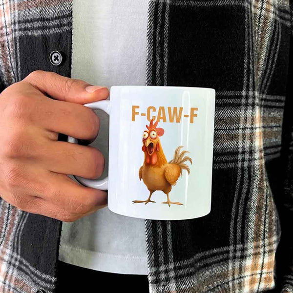 Person holding a mug with a cartoon chicken and 'F-CAW-F' text, wearing a plaid shirt.