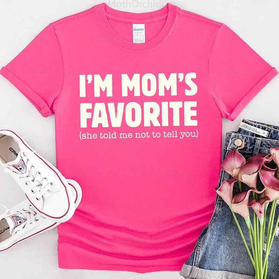 May include a unisex t-shirt reading “I’m Mom’s Favorite” in bold font, displayed on a flat lay or model, ideal for Mother’s Day gifting.