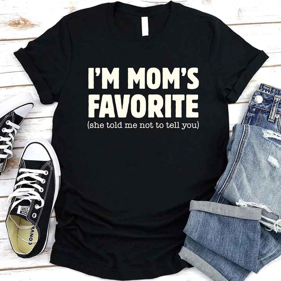 May include a unisex t-shirt reading “I’m Mom’s Favorite” in bold font, displayed on a flat lay or model, ideal for Mother’s Day gifting.