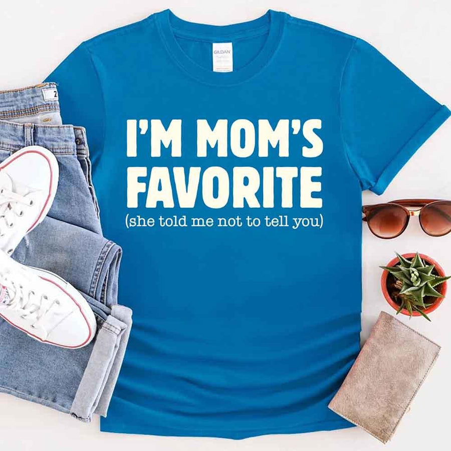 May include a unisex t-shirt reading “I’m Mom’s Favorite” in bold font, displayed on a flat lay or model, ideal for Mother’s Day gifting.