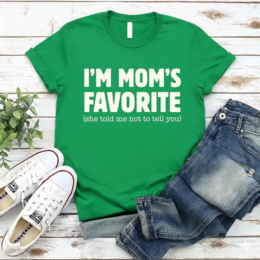 May include a unisex t-shirt reading “I’m Mom’s Favorite” in bold font, displayed on a flat lay or model, ideal for Mother’s Day gifting.