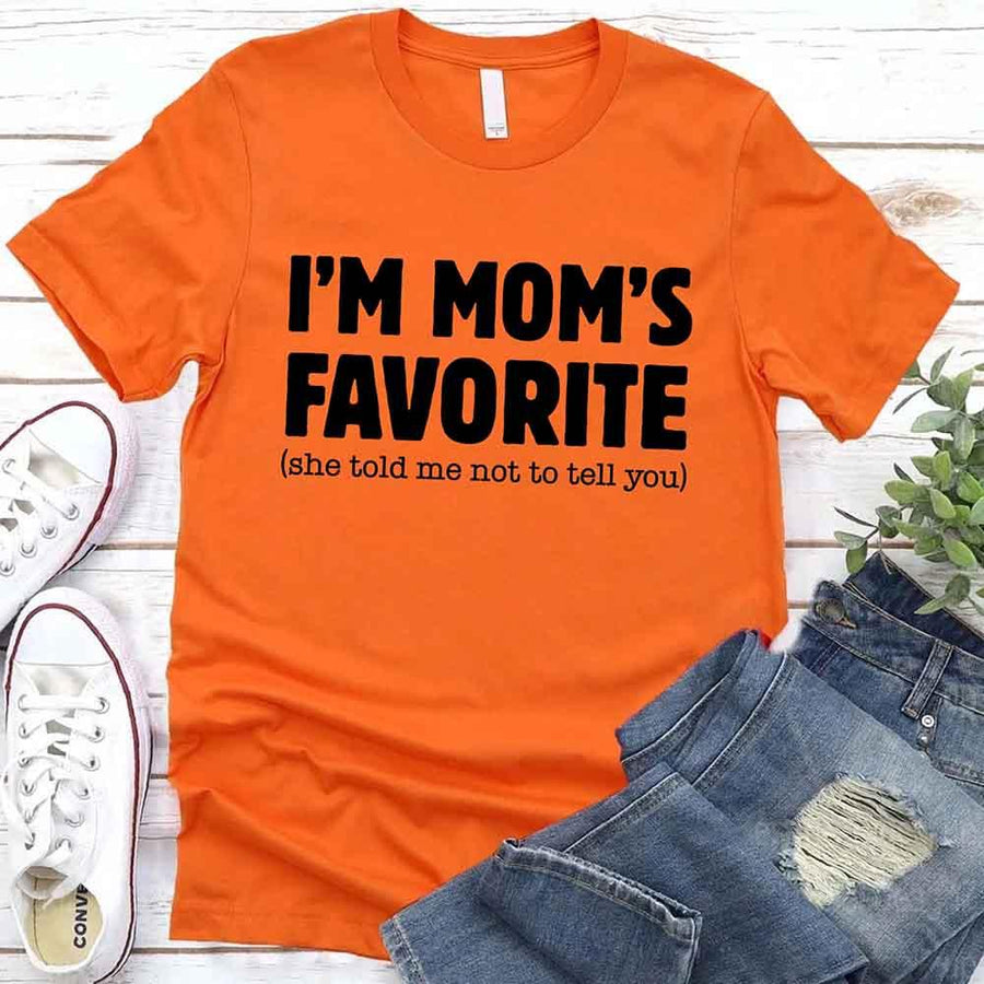 May include a unisex t-shirt reading “I’m Mom’s Favorite” in bold font, displayed on a flat lay or model, ideal for Mother’s Day gifting.