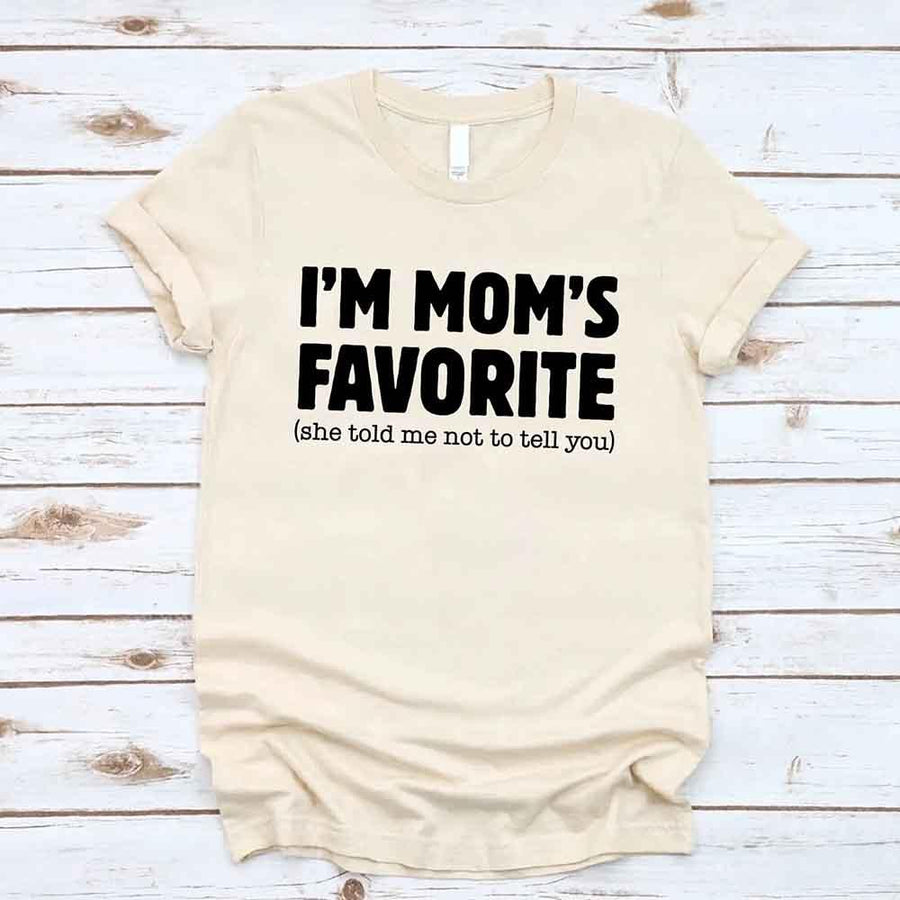 May include a unisex t-shirt reading “I’m Mom’s Favorite” in bold font, displayed on a flat lay or model, ideal for Mother’s Day gifting.