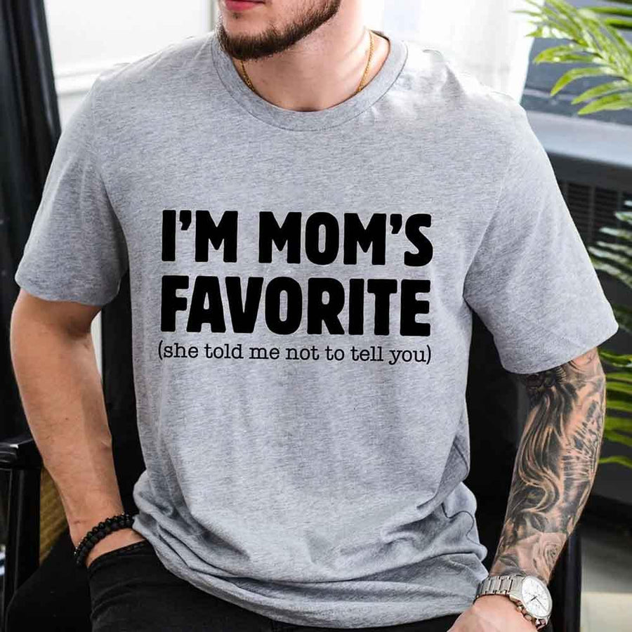 May include a unisex t-shirt reading “I’m Mom’s Favorite” in bold font, displayed on a flat lay or model, ideal for Mother’s Day gifting.