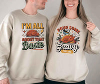 Two people wearing matching sweatshirts with humorous Thanksgiving-themed text and graphics.