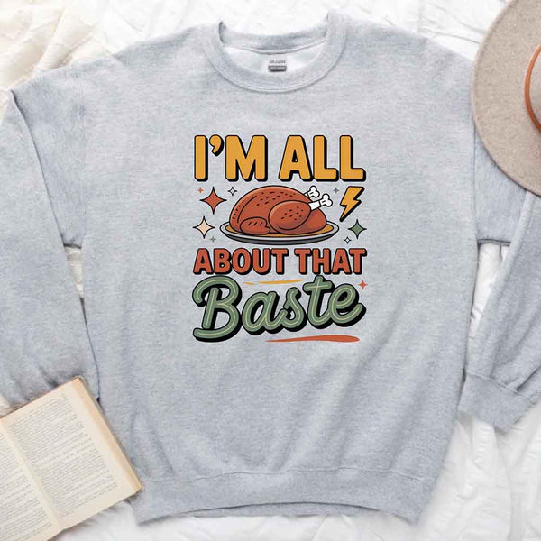 Gray sweatshirt with a graphic of a roasted turkey and text 'I'm All About That Baste' on a white surface.