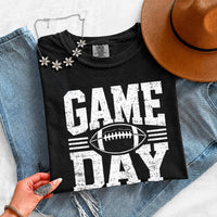 May include a Comfort Colors T-shirt featuring a distressed Game Day graphic with a football design, perfect for football fans, tailgates, watch parties, and sporting events.