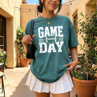 May include a Comfort Colors T-shirt featuring a distressed Game Day graphic with a football design, perfect for football fans, tailgates, watch parties, and sporting events.