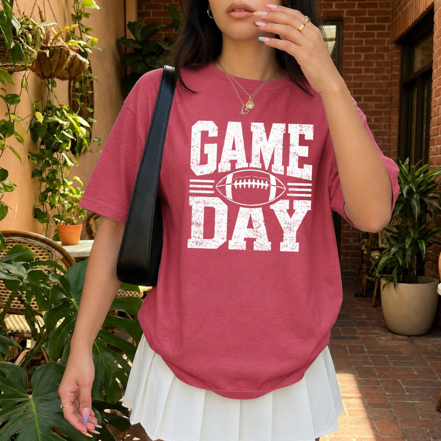 May include a Comfort Colors T-shirt featuring a distressed Game Day graphic with a football design, perfect for football fans, tailgates, watch parties, and sporting events.