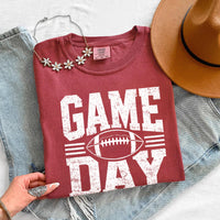 May include a Comfort Colors T-shirt featuring a distressed Game Day graphic with a football design, perfect for football fans, tailgates, watch parties, and sporting events.