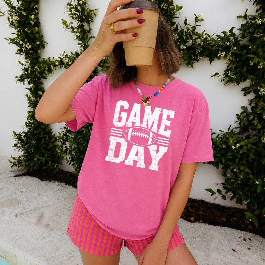 May include a Comfort Colors T-shirt featuring a distressed Game Day graphic with a football design, perfect for football fans, tailgates, watch parties, and sporting events.