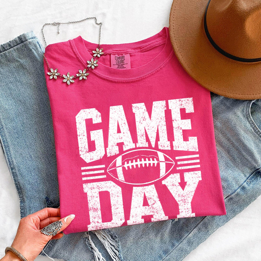 May include a Comfort Colors T-shirt featuring a distressed Game Day graphic with a football design, perfect for football fans, tailgates, watch parties, and sporting events.
