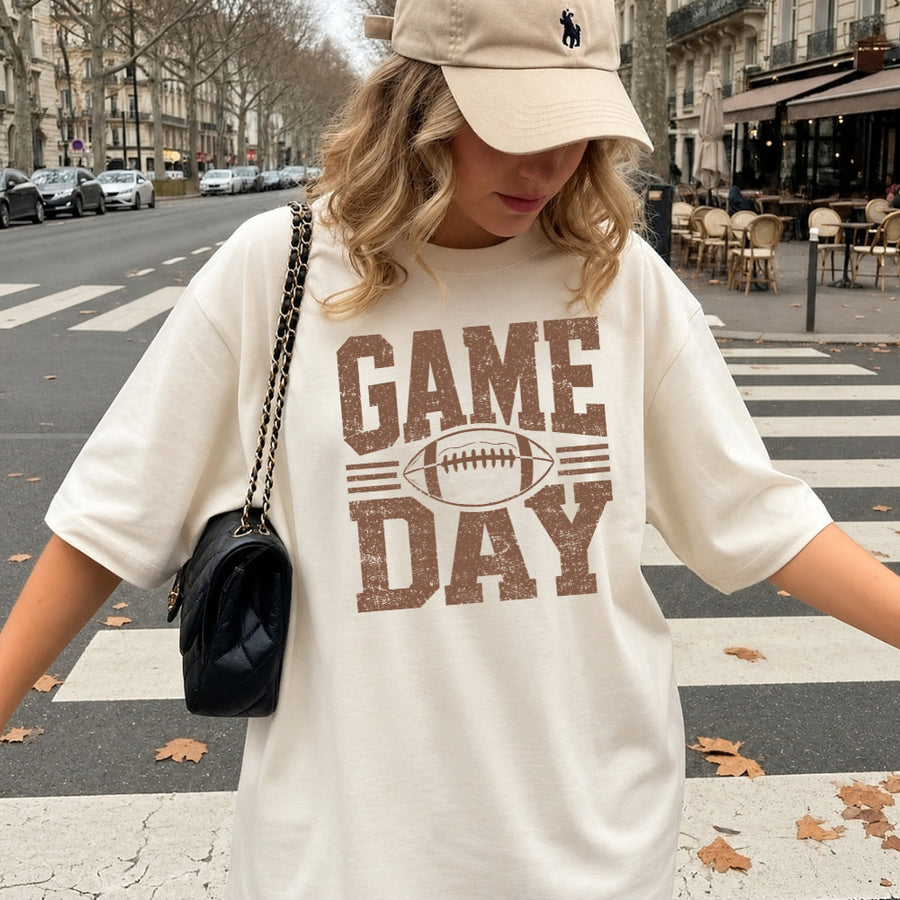 May include a Comfort Colors T-shirt featuring a distressed Game Day graphic with a football design, perfect for football fans, tailgates, watch parties, and sporting events.