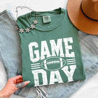 May include a Comfort Colors T-shirt featuring a distressed Game Day graphic with a football design, perfect for football fans, tailgates, watch parties, and sporting events.