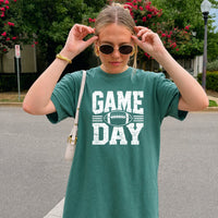 May include a Comfort Colors T-shirt featuring a distressed Game Day graphic with a football design, perfect for football fans, tailgates, watch parties, and sporting events.