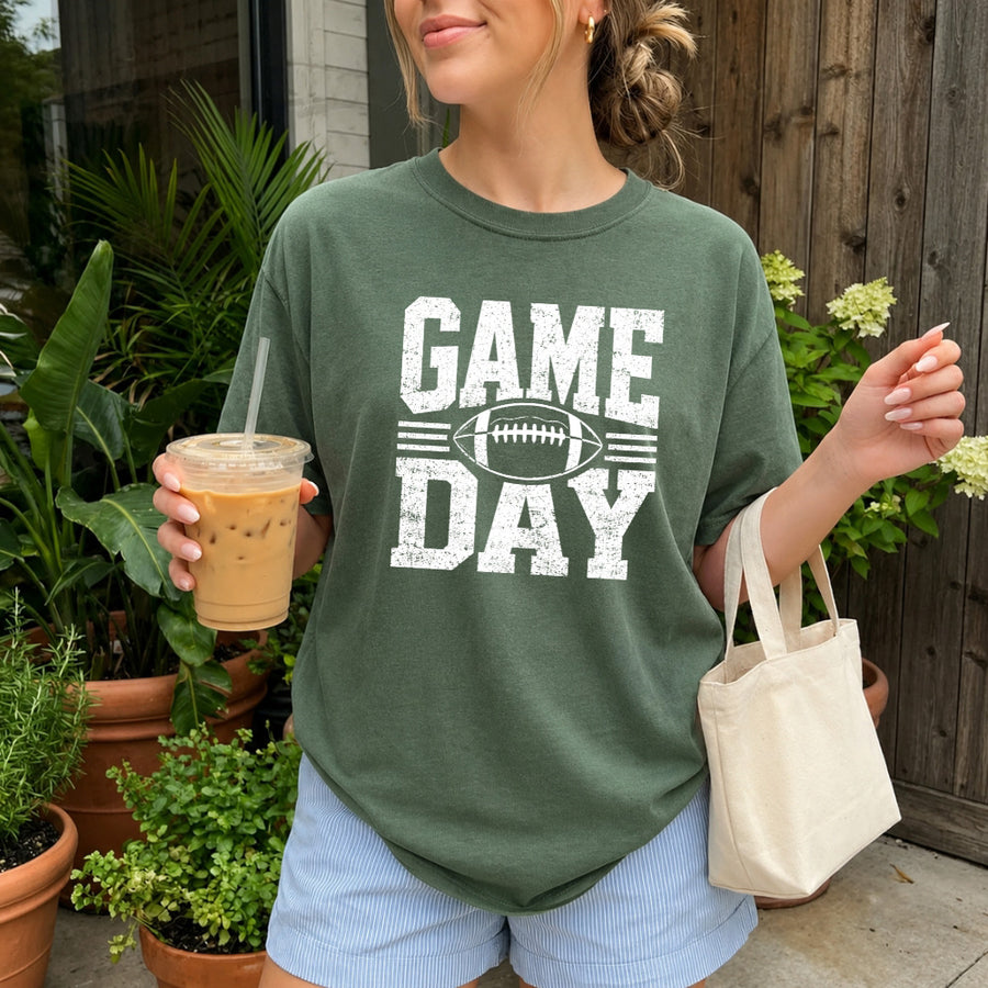 May include a Comfort Colors T-shirt featuring a distressed Game Day graphic with a football design, perfect for football fans, tailgates, watch parties, and sporting events.