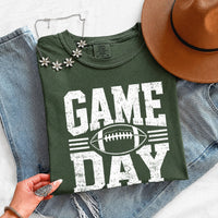 May include a Comfort Colors T-shirt featuring a distressed Game Day graphic with a football design, perfect for football fans, tailgates, watch parties, and sporting events.