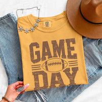 May include a Comfort Colors T-shirt featuring a distressed Game Day graphic with a football design, perfect for football fans, tailgates, watch parties, and sporting events.
