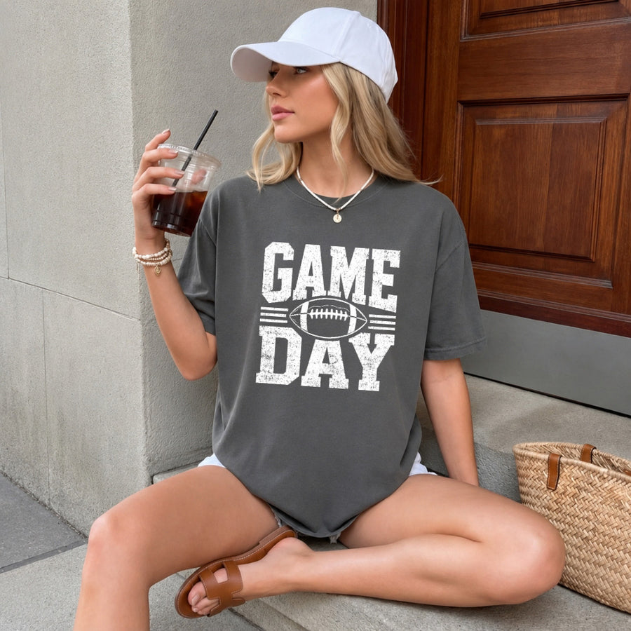 May include a Comfort Colors T-shirt featuring a distressed Game Day graphic with a football design, perfect for football fans, tailgates, watch parties, and sporting events.