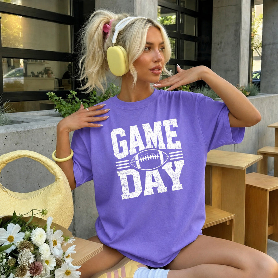 May include a Comfort Colors T-shirt featuring a distressed Game Day graphic with a football design, perfect for football fans, tailgates, watch parties, and sporting events.