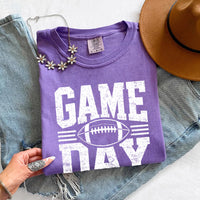 May include a Comfort Colors T-shirt featuring a distressed Game Day graphic with a football design, perfect for football fans, tailgates, watch parties, and sporting events.
