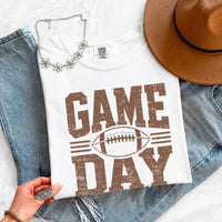 May include a Comfort Colors T-shirt featuring a distressed Game Day graphic with a football design, perfect for football fans, tailgates, watch parties, and sporting events.
