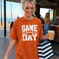 May include a Comfort Colors T-shirt featuring a distressed Game Day graphic with a football design, perfect for football fans, tailgates, watch parties, and sporting events.