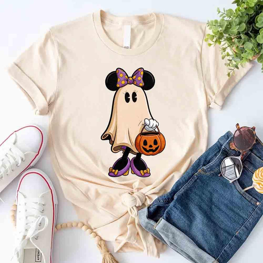 Beige t-shirt with a ghost character holding a pumpkin, paired with jeans and sneakers on a light background.