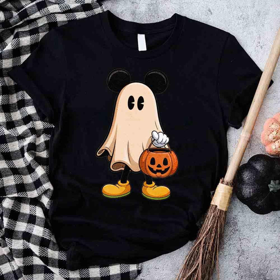 Black t-shirt with a ghost design holding a pumpkin, placed on a checkered cloth with Halloween decorations.