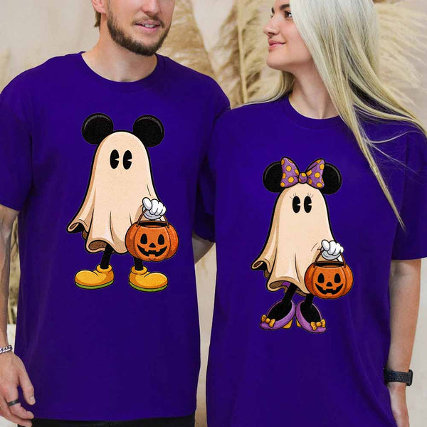Two people wearing halloween purple t-shirts with ghost designs holding pumpkins.