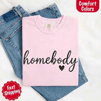May include a folded blossom Comfort Colors “homebody” t-shirt in neutral tones, with minimalist black lettering and heart detail, laid on denim jeans.