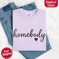 May include a folded orchid Comfort Colors “homebody” t-shirt in neutral tones, with minimalist black lettering and heart detail, laid on denim jeans.