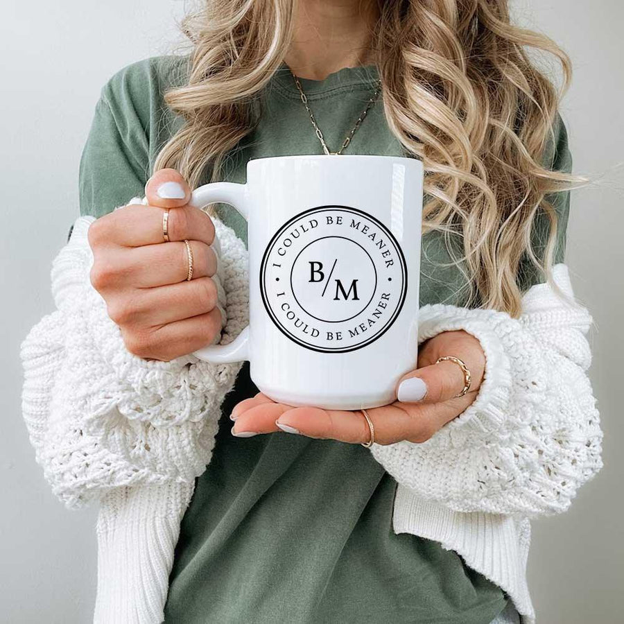 Person holding a white mug with a logo and text, wearing a green sweater and white cardigan.