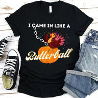 May include a casual crew-neck T-shirt with a playful Thanksgiving graphic showing a turkey stepping onto or perched on a pumpkin, surrounded by leaves or autumn motifs, with bold front text reading “I Came In Like A Butterball.”