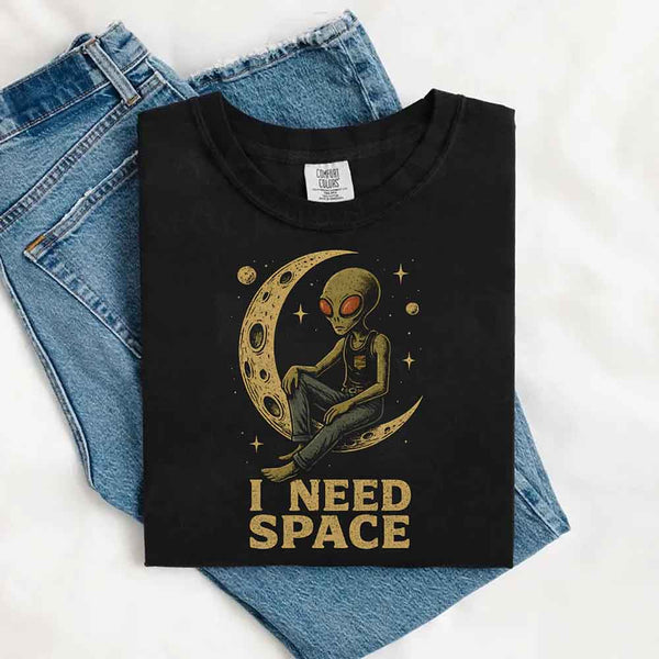 May include a folded BlackComfort Colors T-shirt with “i need space” printed in a gothic font, laid over denim jeans for a bold, moody, and alternative vibe.