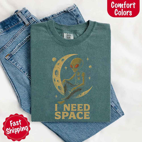 May include a folded black Comfort Colors T-shirt with “i need space” printed in a gothic font, laid over denim jeans for a bold, moody, and alternative vibe.