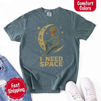 May include a folded black Comfort Colors T-shirt with “i need space” printed in a gothic font, laid over denim jeans for a bold, moody, and alternative vibe.