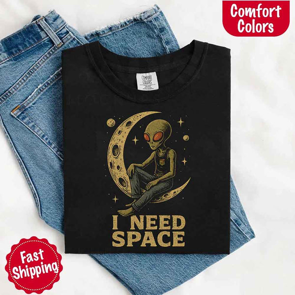 May include a folded black Comfort Colors T-shirt with “i need space” printed in a gothic font, laid over denim jeans for a bold, moody, and alternative vibe.