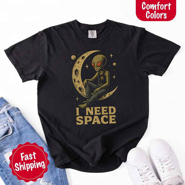May include a flatlay black Comfort Colors T-shirt with “i need space” printed in a gothic font, laid over denim jeans for a bold, moody, and alternative vibe.