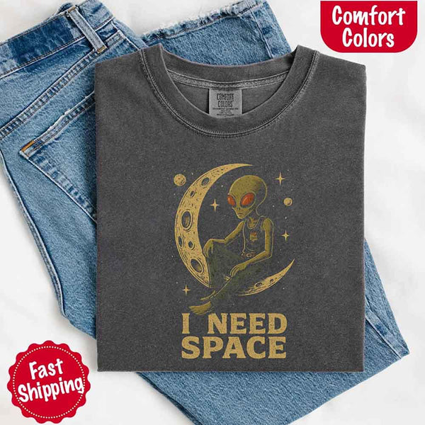 May include a folded Pepper Comfort Colors T-shirt with “i need space” printed in a gothic font, laid over denim jeans for a bold, moody, and alternative vibe.