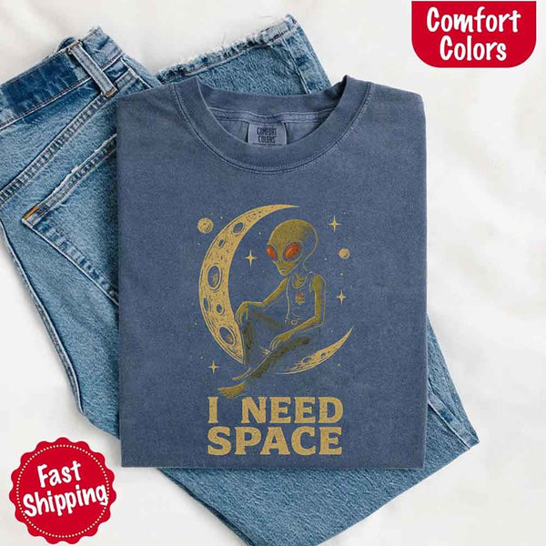 May include a folded black Comfort Colors T-shirt with “i need space” printed in a gothic font, laid over denim jeans for a bold, moody, and alternative vibe.