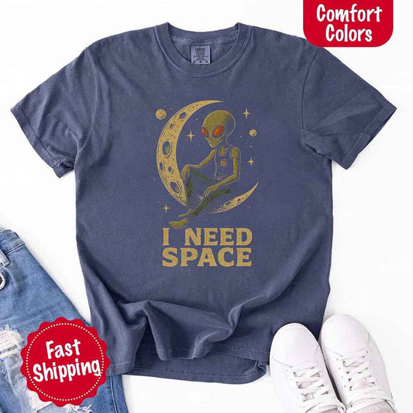 May include a folded black Comfort Colors T-shirt with “i need space” printed in a gothic font, laid over denim jeans for a bold, moody, and alternative vibe.