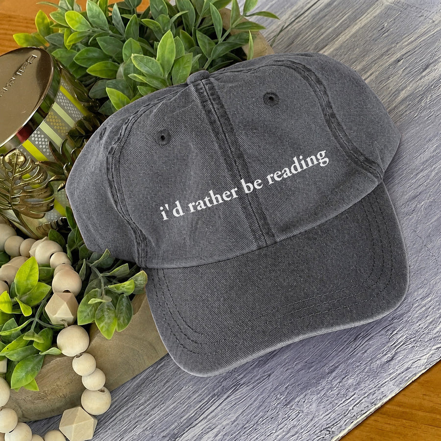 May include an I’d Rather Be Reading Pigment-Dyed Cap featuring a book lover statement on a casual pigment-dyed baseball cap.