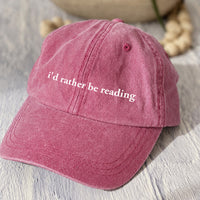 May include an I’d Rather Be Reading Pigment-Dyed Cap featuring a book lover statement on a casual pigment-dyed baseball cap.