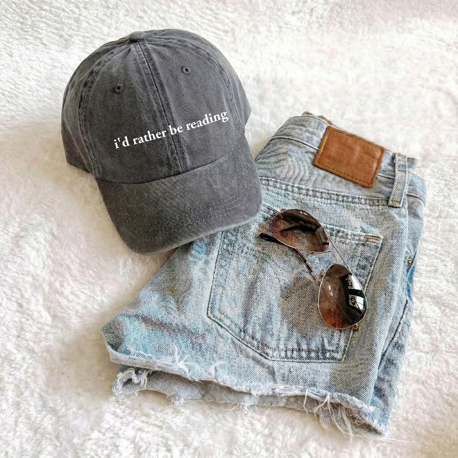 May include an I’d Rather Be Reading Pigment-Dyed Cap featuring a book lover statement on a casual pigment-dyed baseball cap.